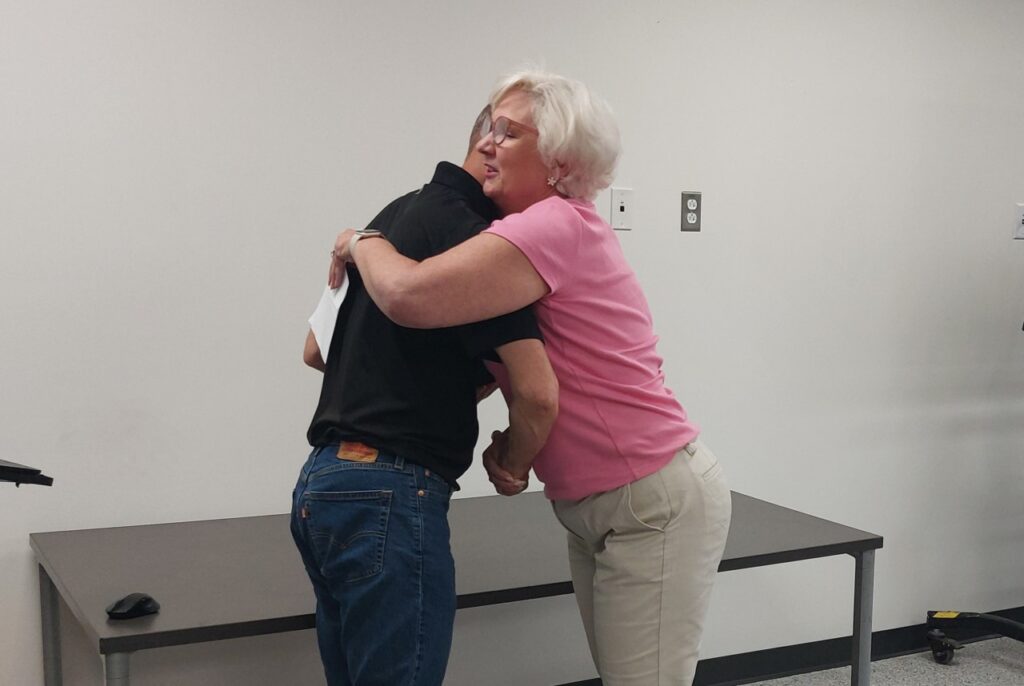 KrisTech VP of Sales Kris McCarty hugs Employee of the Month winner Steve Pietrowski.