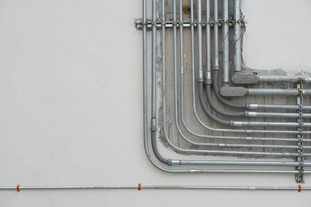 Electrical conduit system and metal pipeline installed on a building ceiling. (Shutterstock)