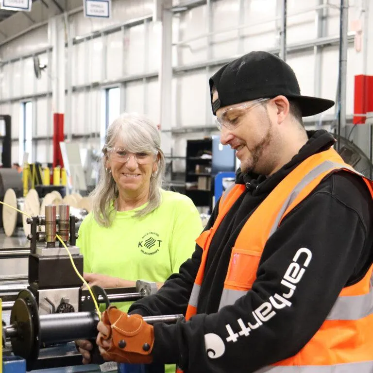 Two KrisTech Wire team members train together on a wire respooling machine. - KrisTech Wire (Photo via Gino Geruntino)