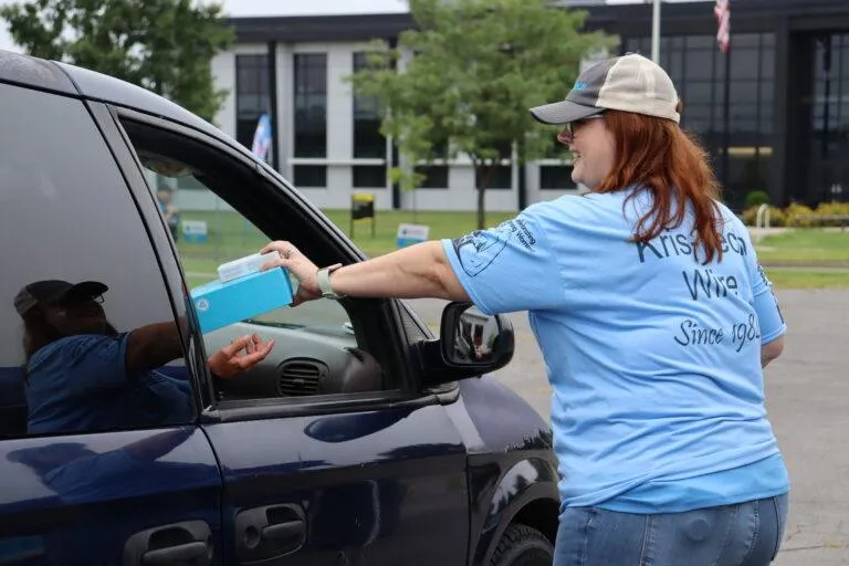 A KrisTech employee hands out school supplies during one of the company’s back-to-school donation events at its Rome, NY campus. Photo by Gino Geruntino.