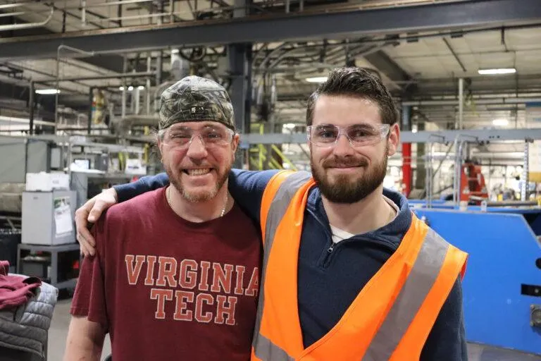 Two KrisTech Wire employees pose for a photo while on the production floor. Photo by Gino Geruntino.