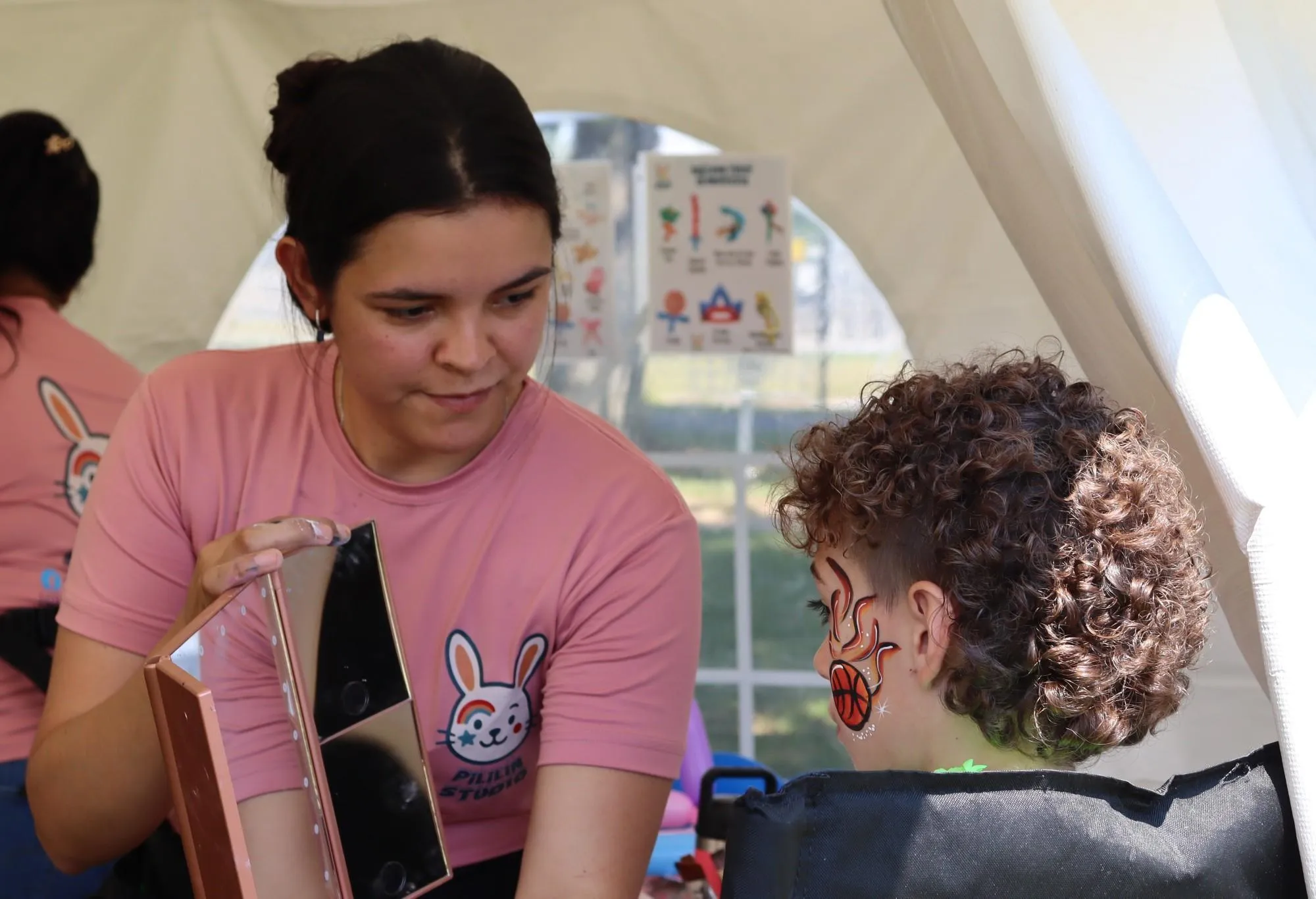 A face painter shows off her work to a happy customer during the KrisTech summer picnic. Photo by Gino Geruntino.