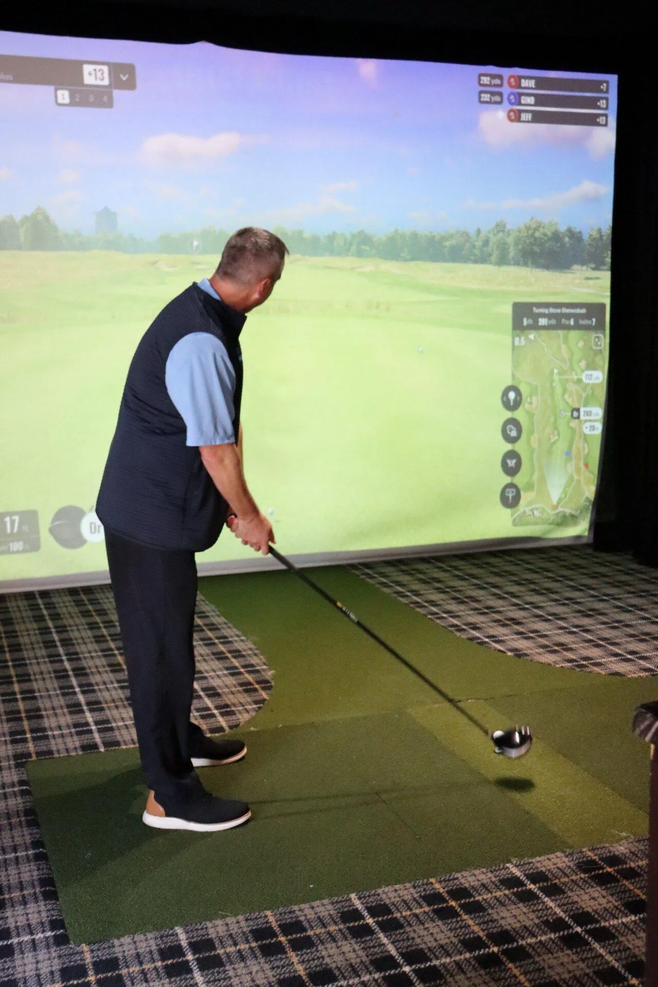 A KT employee sets his club before swinging during KrisTech's virtual golf event. Photo by Gino Geruntino.