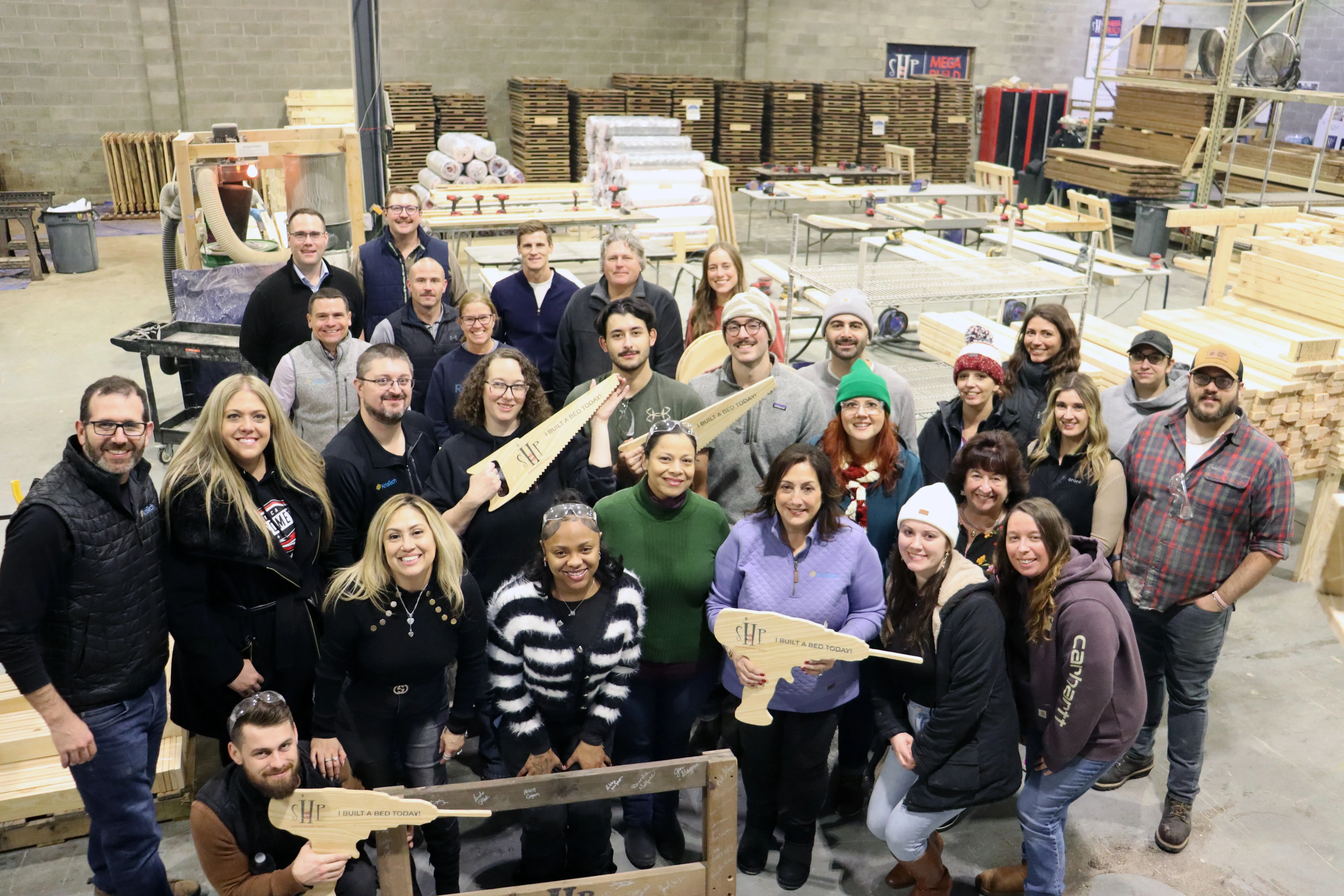 A group of KrisTech employees assembles beds for children living in the Mohawk Valley through a charity build event hosted by Sleep in Heavenly Peace. Photo by Gino Geruntino.