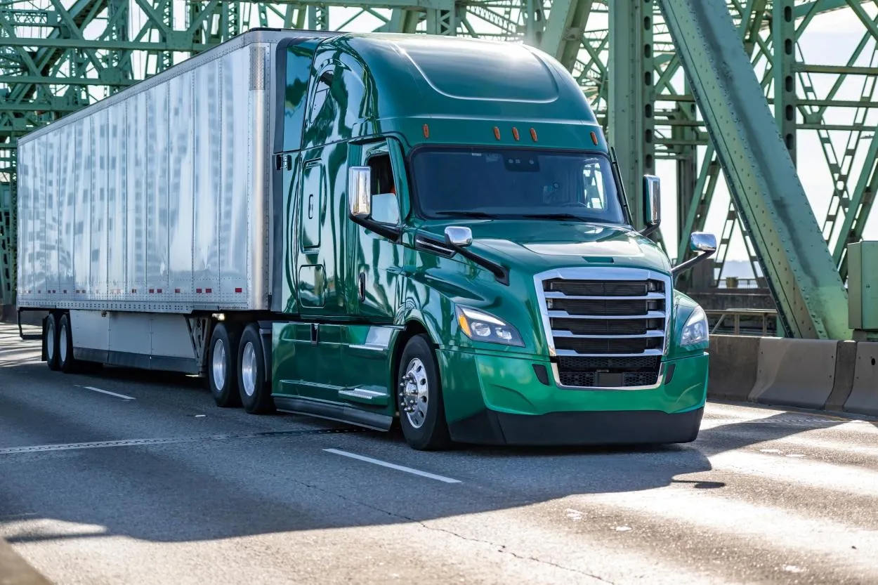 A tractor trailer crosses a bridge on a sunny day. - KrisTech Wire, photo via Shutterstock
