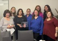 A group of KrisTech employees smile as they pose with an award presented by Make-A-Wish Central New York.